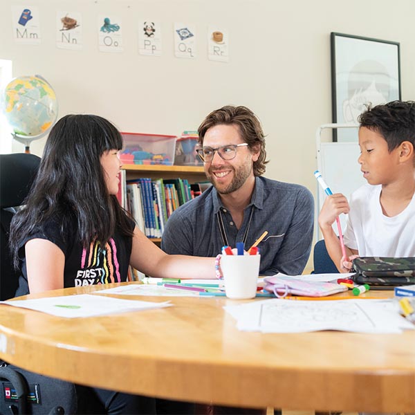 An adult in a classroom setting with two children